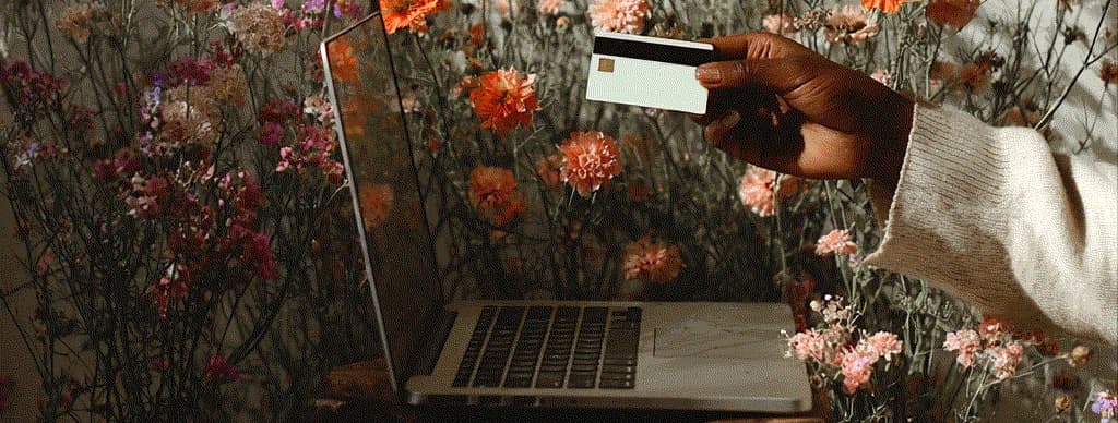 Person working on laptop surrounded by flowers